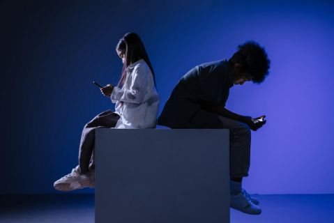 Niños sentados en habitación con teléfonos móviles