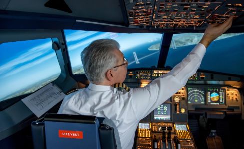  Piloto en la cabina de mando de un avión comercial, supervisando los instrumentos de vuelo y los sistemas de navegación durante la operación.
